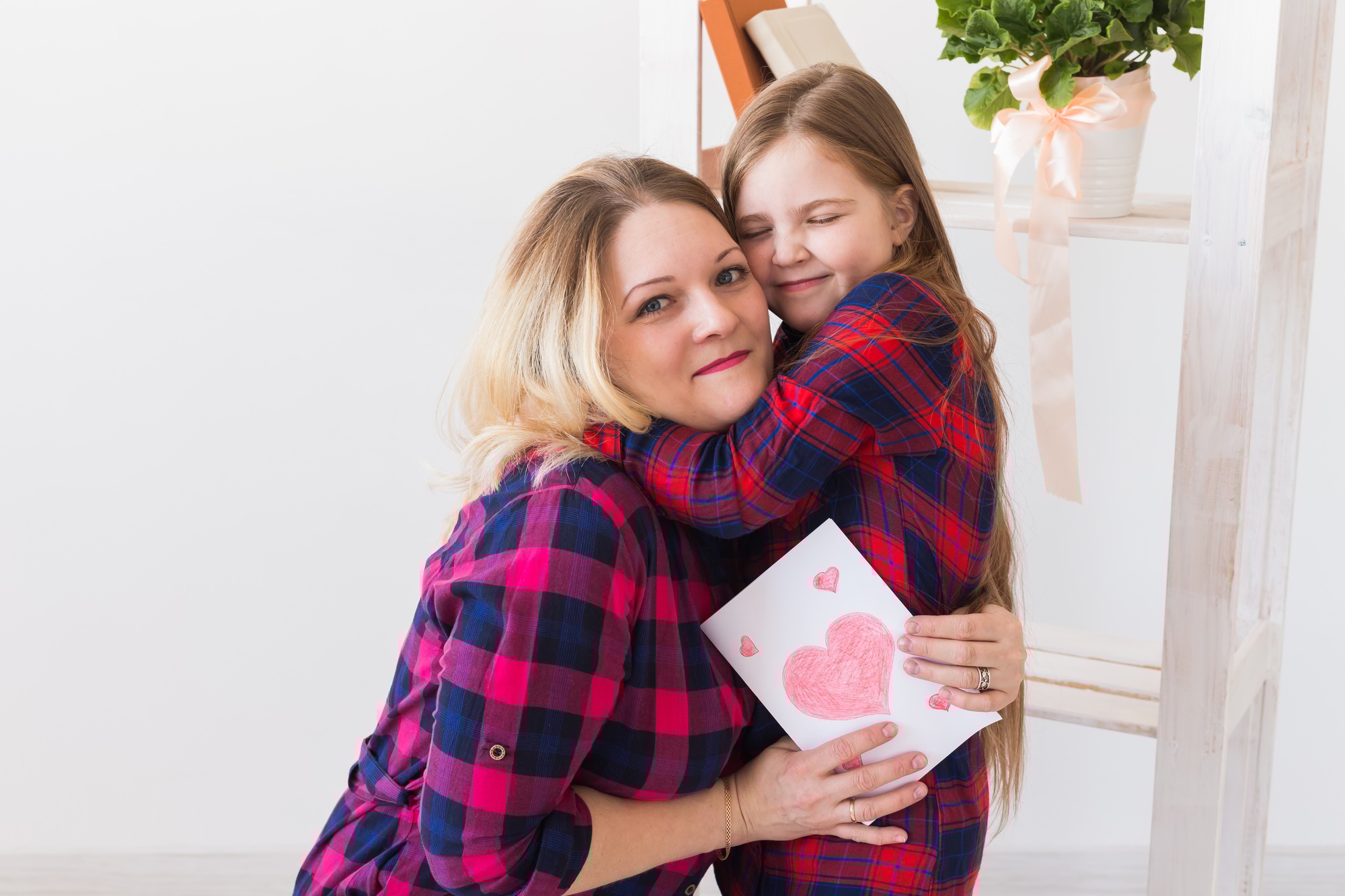 Happy mother's day. Child daughter congratulates mom and gives her postcard. Mum and kid girl