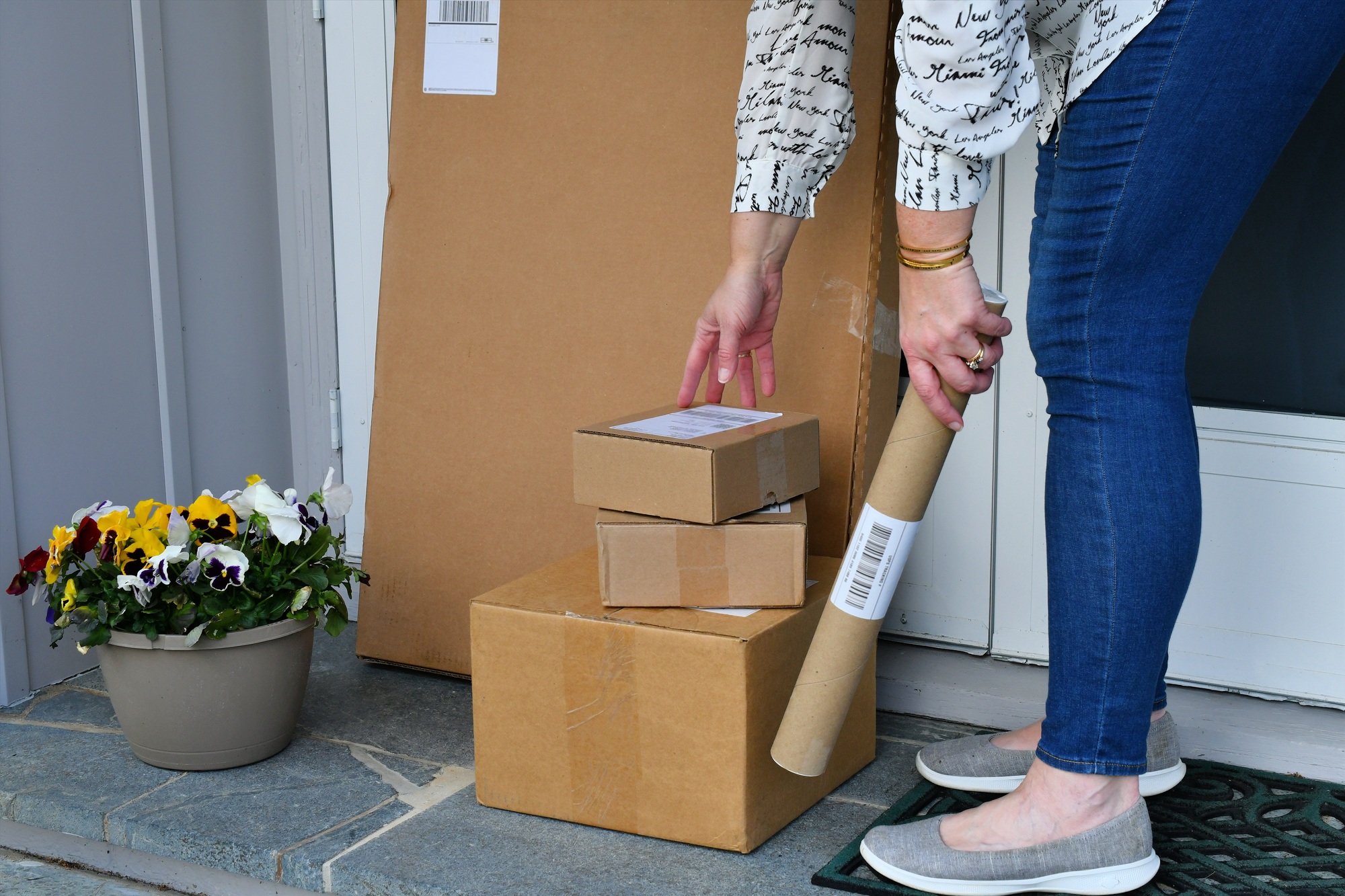 Woman picking up packages ordered online boxes off the front porch after they were delivered