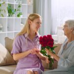 Young girl gives flowers to aged lady with joyful smile at birthday